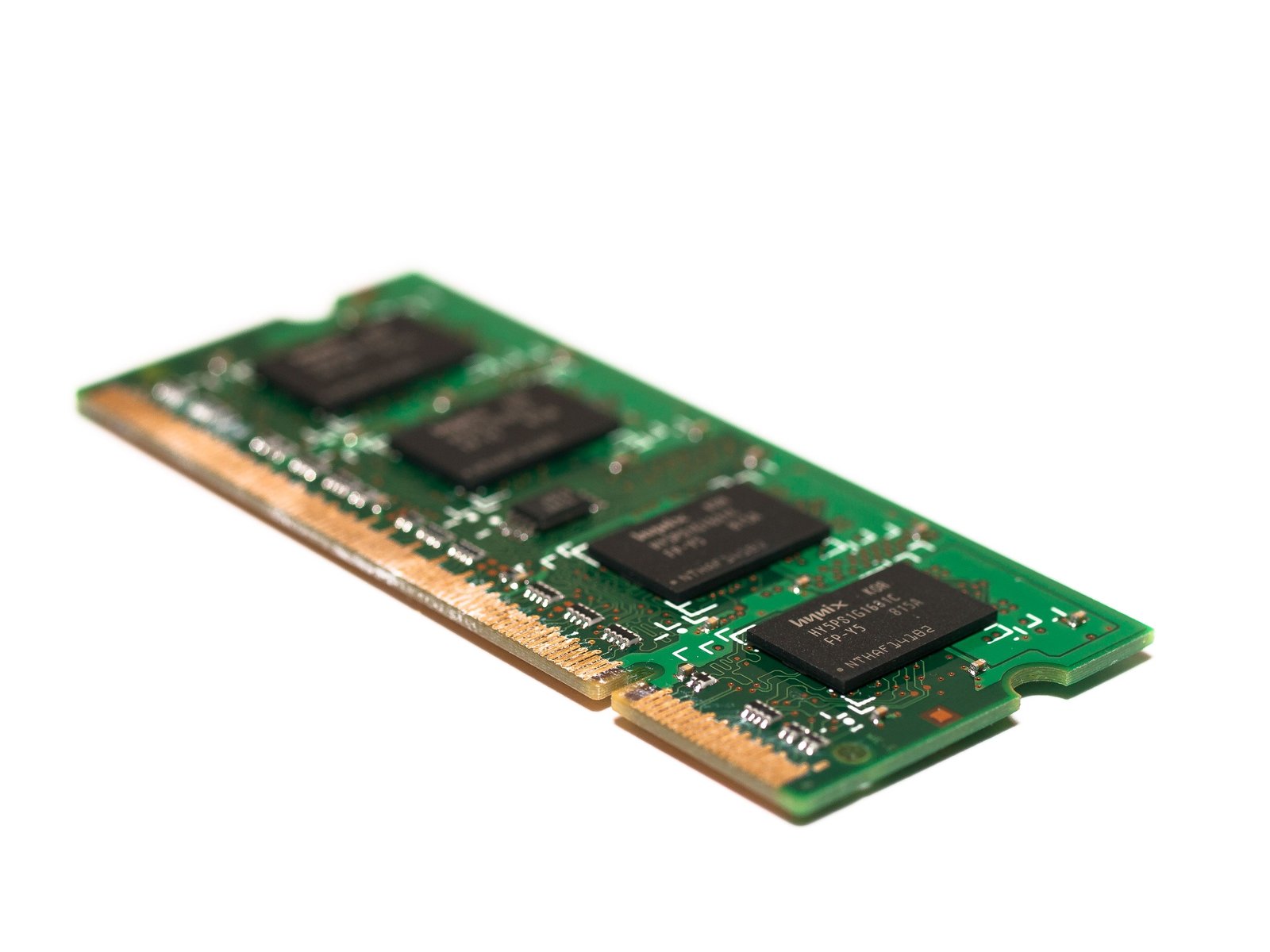 Close-up of a memory module — green PCB with gold contacts