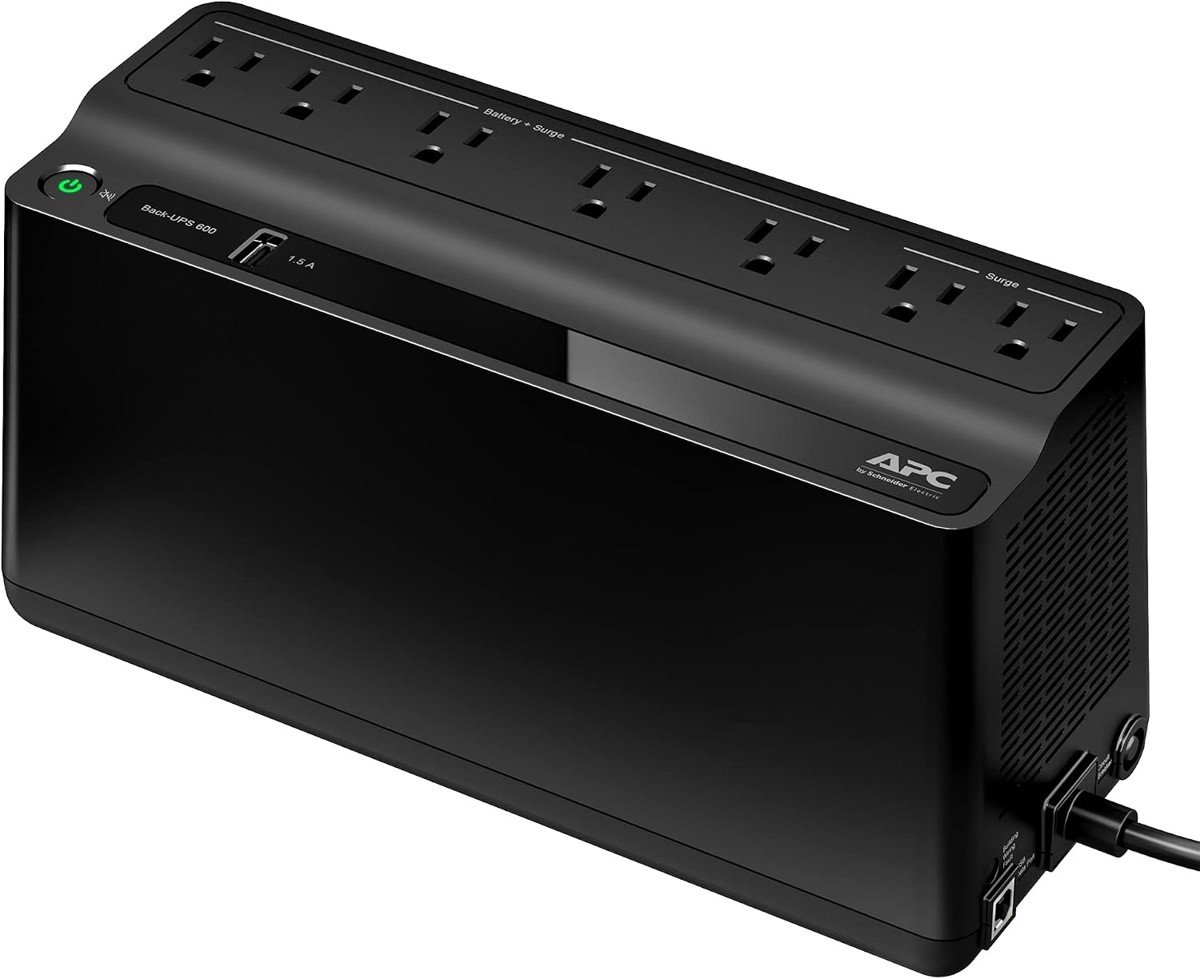 APC Back-UPS BE600M1, a black rectangular battery backup with seven outlets on top, five labeled battery plus surge and two labeled surge, and a USB port and power button on the front
