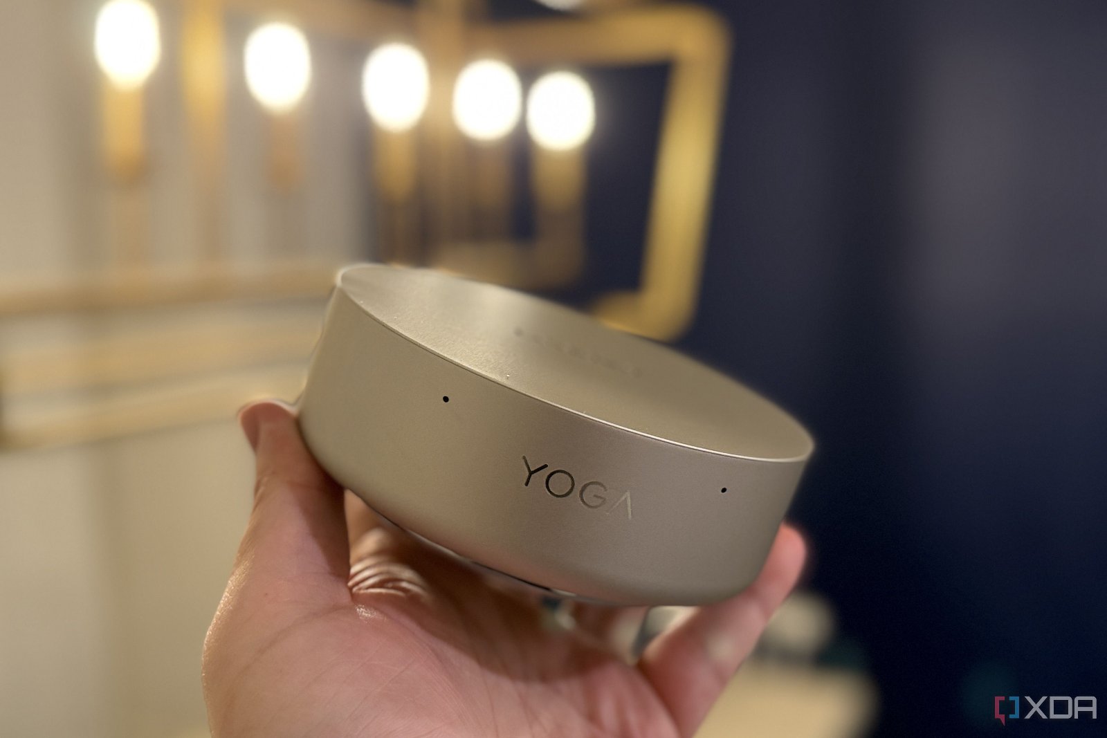 Person holding the circular Lenovo Yoga Mini PC